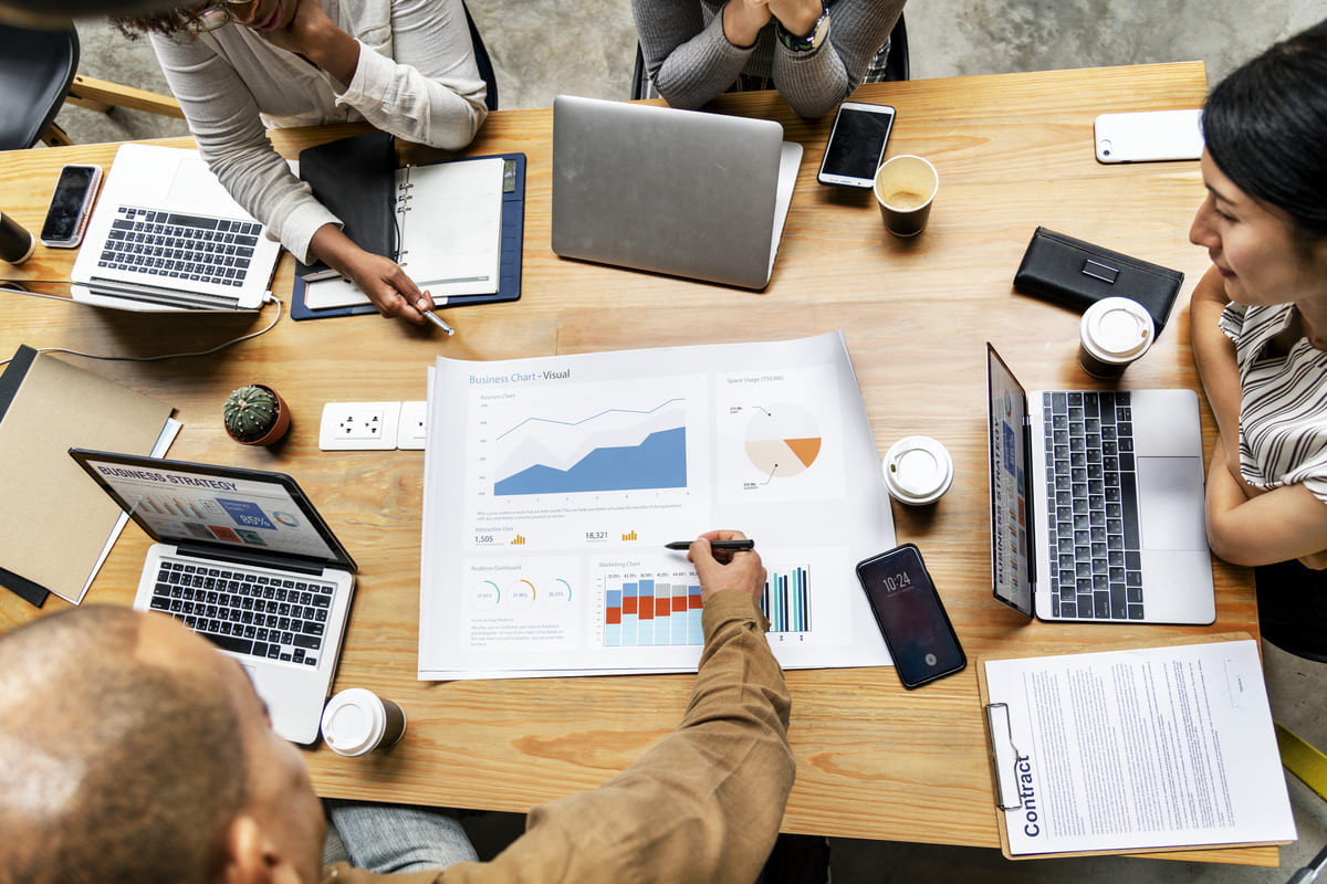 Equipo de trabajo alrededor de una mesa revisando gráficos de resultados y planes de negocio